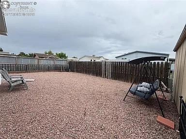 Image 30 of 34: Gravel-covered backyard featuring a wood privacy fence and a detached stora