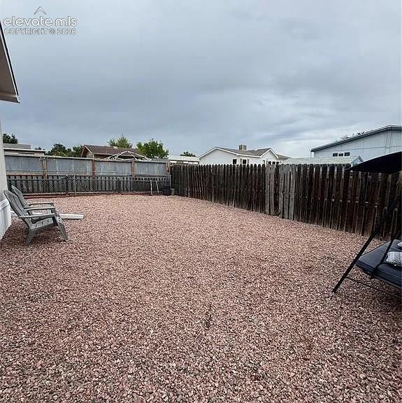 Image 31 of 34: Expansive backyard featuring a full gravel surface, a wood privacy fence, a