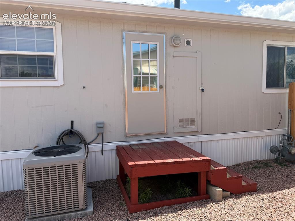Image 33 of 34: Rear exterior featuring light-colored siding, a multi-pane entry door, and 