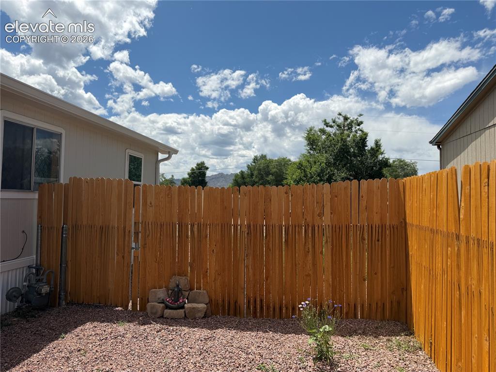 Image 34 of 34: Private outdoor space featuring a new wood fence with gate, gravel ground c