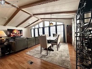Image 5 of 34: Vaulted ceiling with exposed wood beams highlights this open living and din