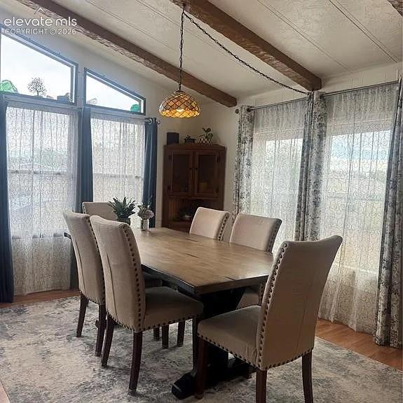 Image 6 of 34: Dining space featuring a vaulted ceiling with exposed wood-finish beams, a 