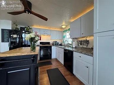 Image 9 of 34: Kitchen featuring a wood-finish floor, black appliances, white cabinetry, a