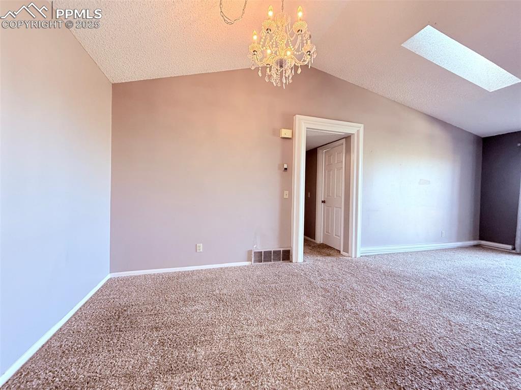 Image 14 of 35: Additional living space with lofted ceiling, carpet, a skylight, a textured