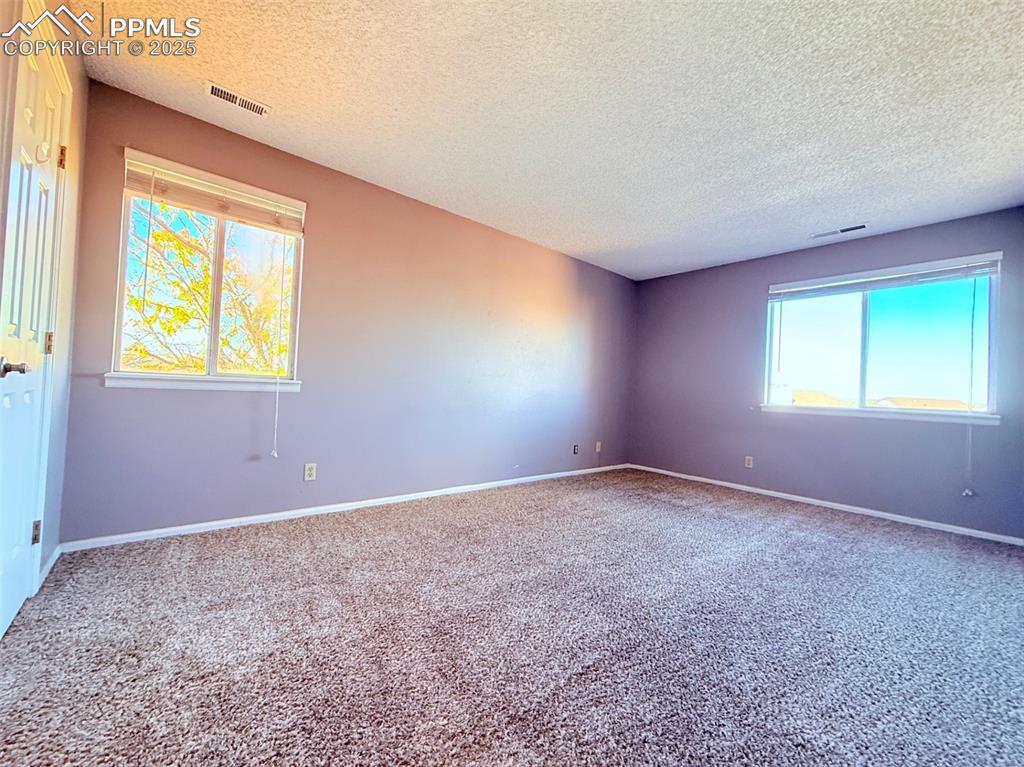 Image 16 of 35: Carpeted spare room with a textured ceiling and baseboards