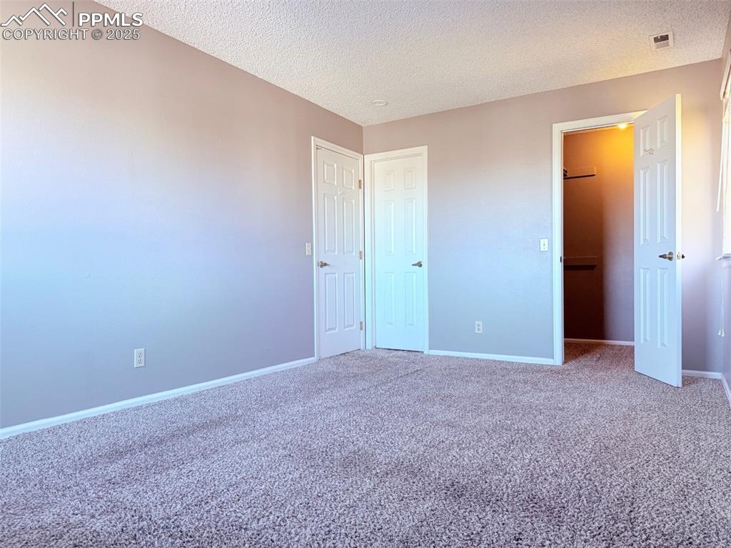 Image 18 of 35: Unfurnished bedroom featuring carpet floors, a textured ceiling, and a spac