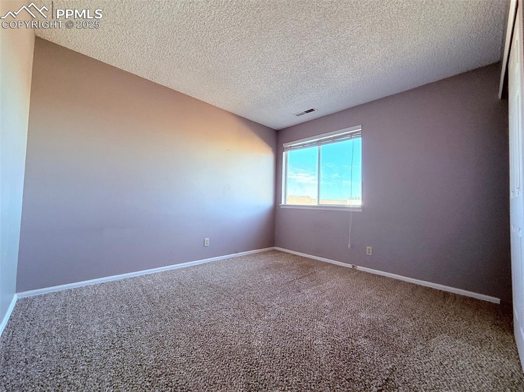 Image 22 of 35: Carpeted empty room featuring a textured ceiling and baseboards
