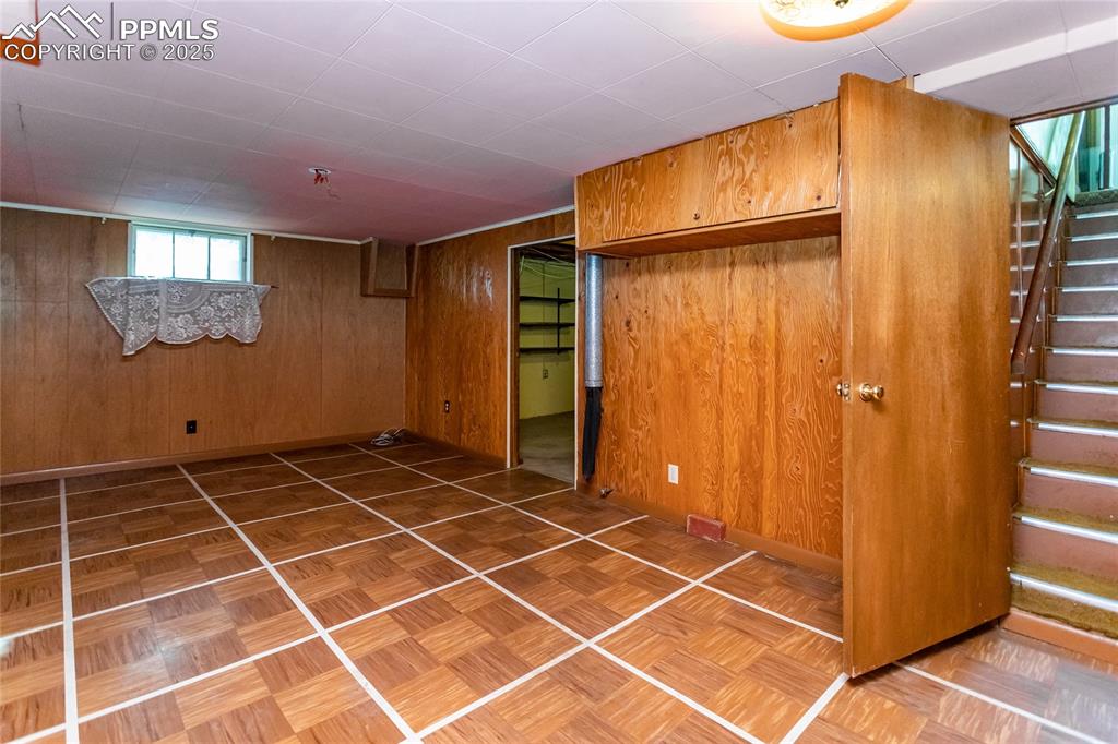 Image 13 of 24: Basement with wooden walls and stairs