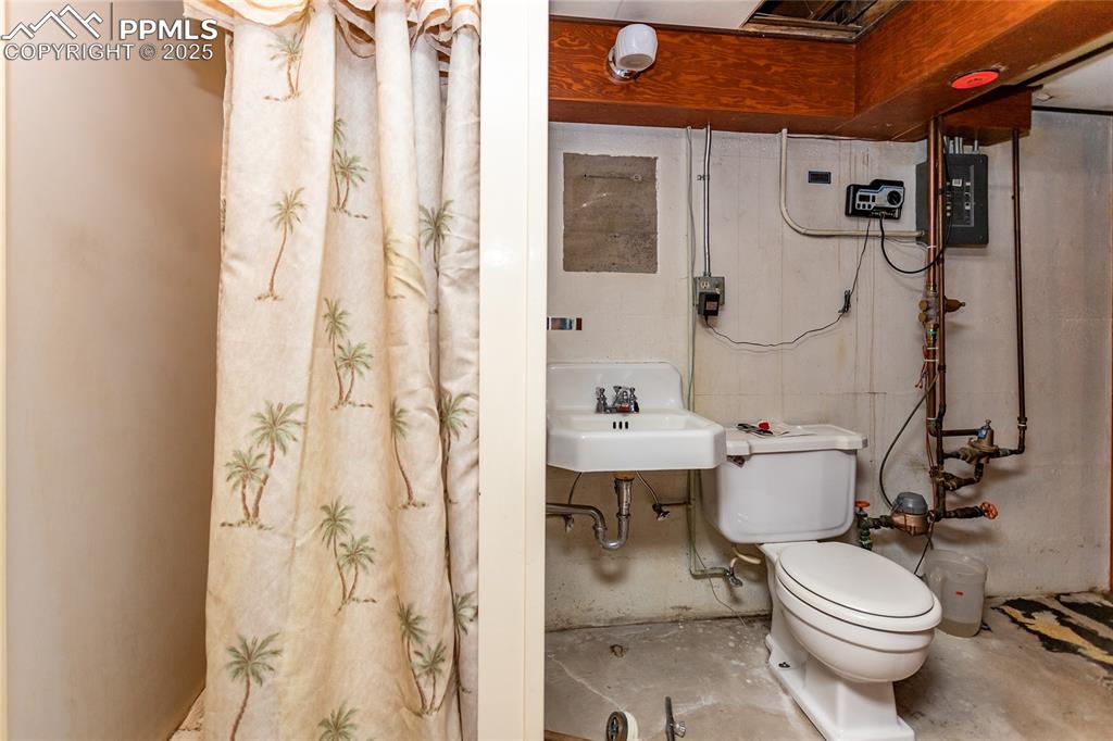 Image 15 of 24: Bathroom featuring curtained shower, unfinished concrete floors, and electr