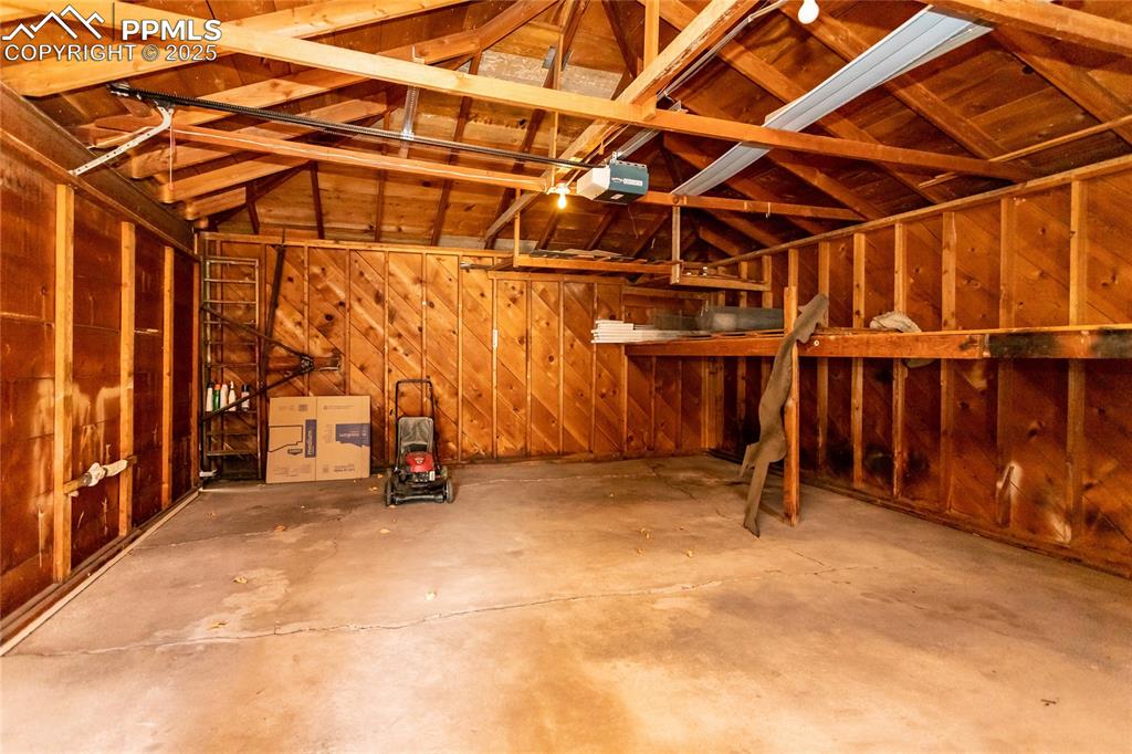 Image 20 of 24: Garage featuring wooden walls and a garage door opener