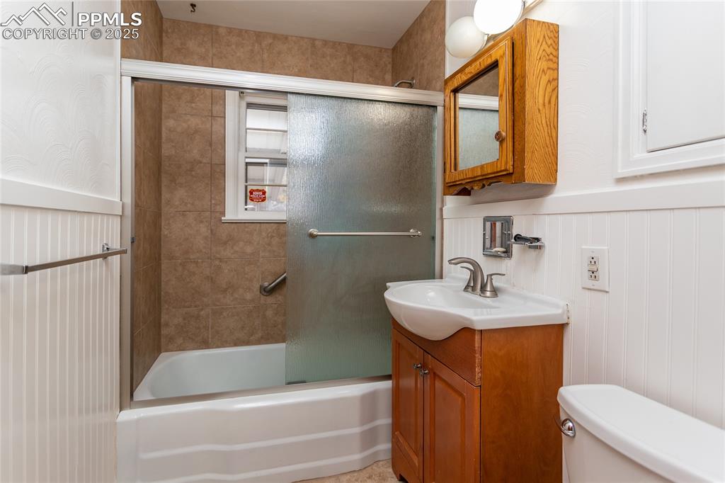Image 9 of 24: Full bath featuring combined bath / shower with glass door, a wainscoted wa