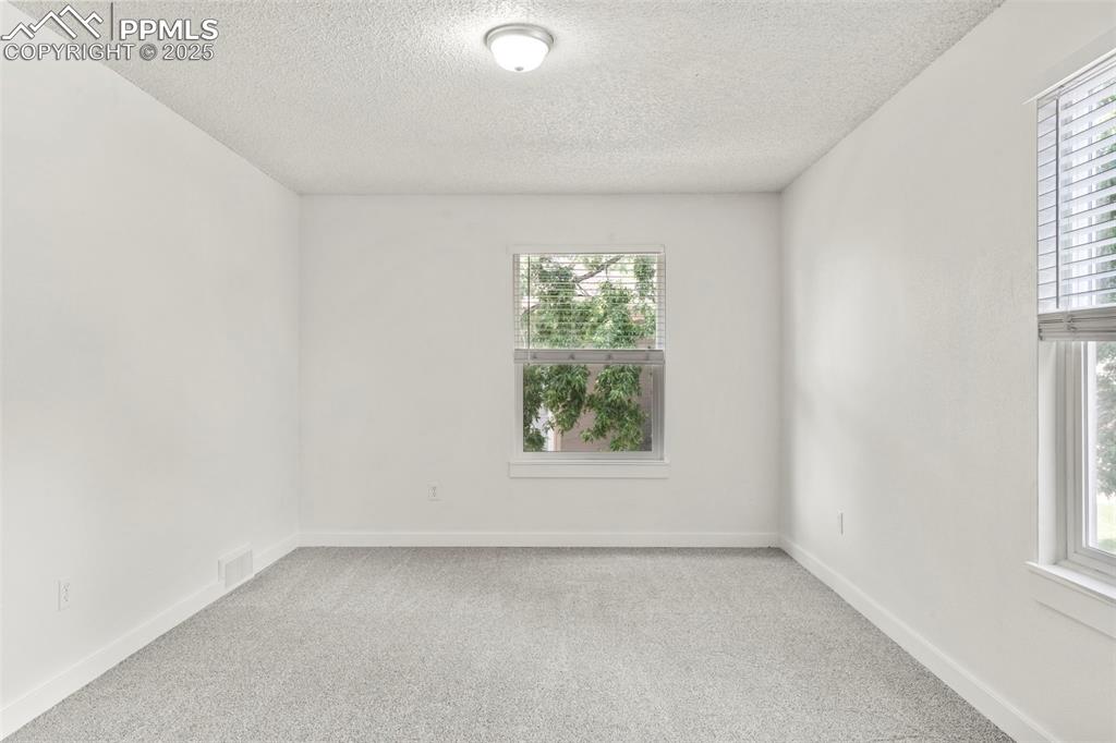 Image 12 of 24: Carpeted spare room with plenty of natural light and a textured ceiling