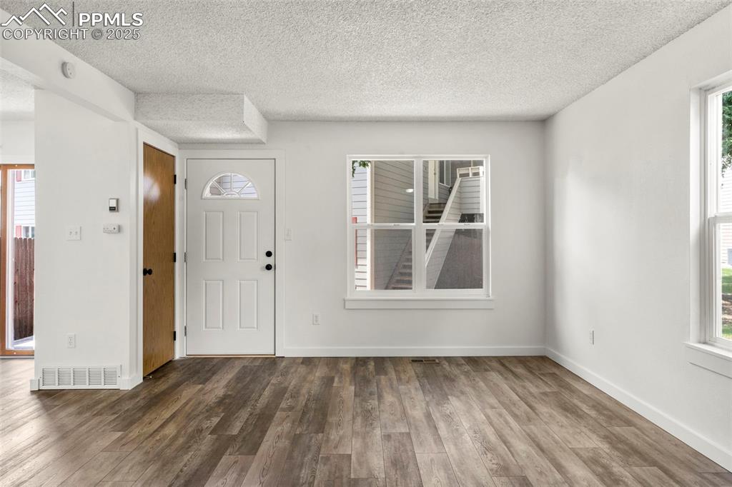 Image 2 of 24: Foyer entrance with plenty of natural light, a textured ceiling, and wood f