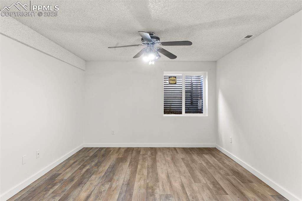 Image 20 of 24: Unfurnished room featuring wood finished floors, a textured ceiling, and a