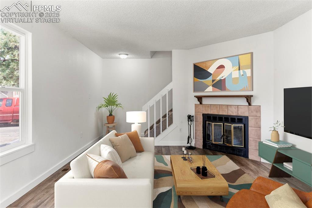 Image 3 of 24: Virtually staged - Living area featuring a tiled fireplace, wood finished f