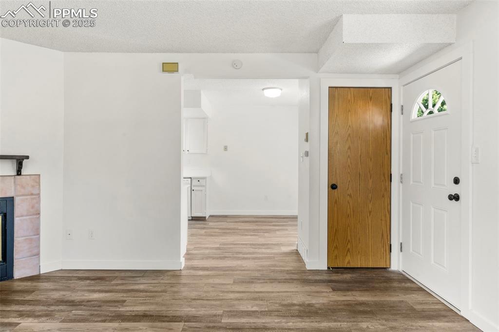 Image 5 of 24: Entryway featuring a textured ceiling, wood finished floors, and a fireplac