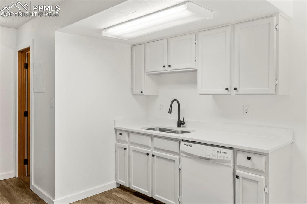 Image 9 of 24: Kitchen featuring white cabinetry, white dishwasher, light wood-type floori