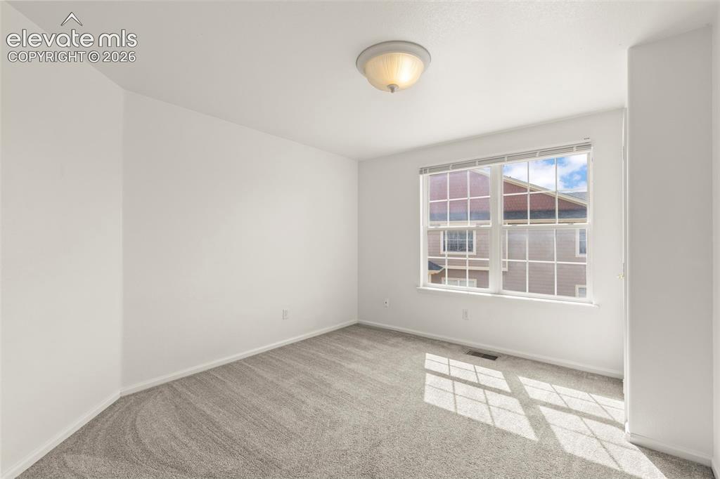 Image 12 of 22: Bright room featuring a large window with white blinds, neutral carpet, and