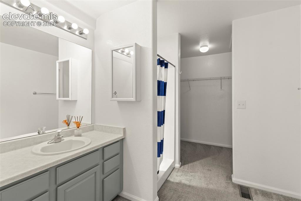 Image 16 of 22: Bathroom featuring a single vanity with grey cabinetry, a built-in sink, an