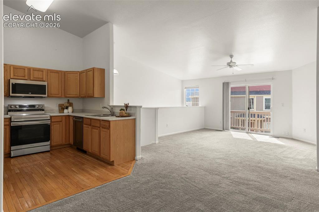 Image 3 of 22: Open-concept living space featuring a kitchen with wood-finish cabinetry an