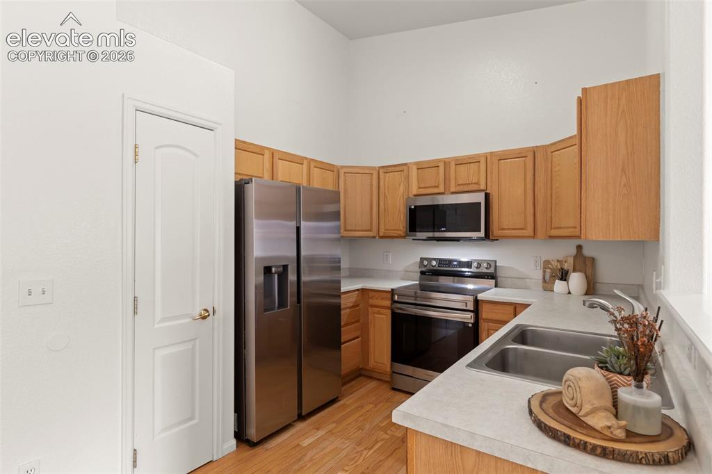Image 4 of 22: Kitchen featuring wood-finish flooring, stainless steel appliances, light w