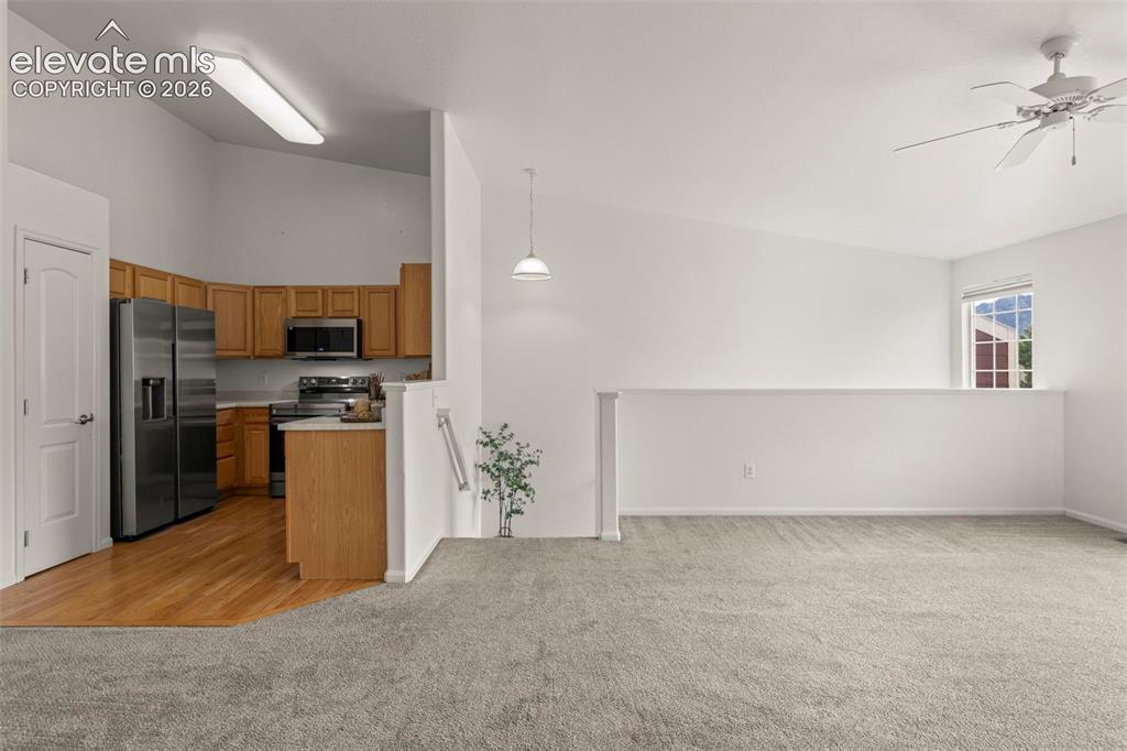 Image 6 of 22: Open-concept living space featuring a vaulted ceiling and a ceiling fan