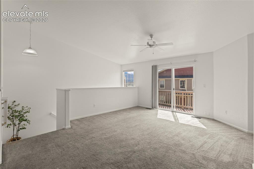 Image 7 of 22: Carpeted loft area with a ceiling fan, pendant light, and sliding glass doo