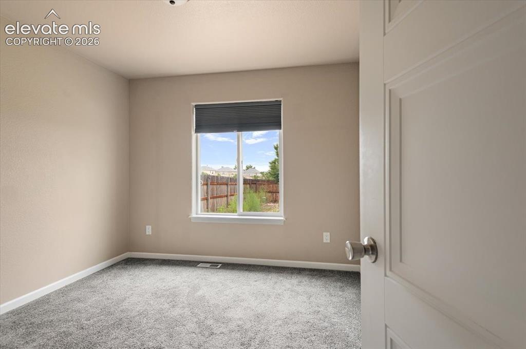 Image 16 of 21: Neutral-toned interior room featuring light gray carpeting and a large wind