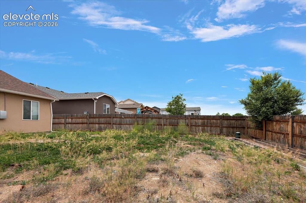 Image 21 of 21: Expansive backyard with a full wooden privacy fence and established trees