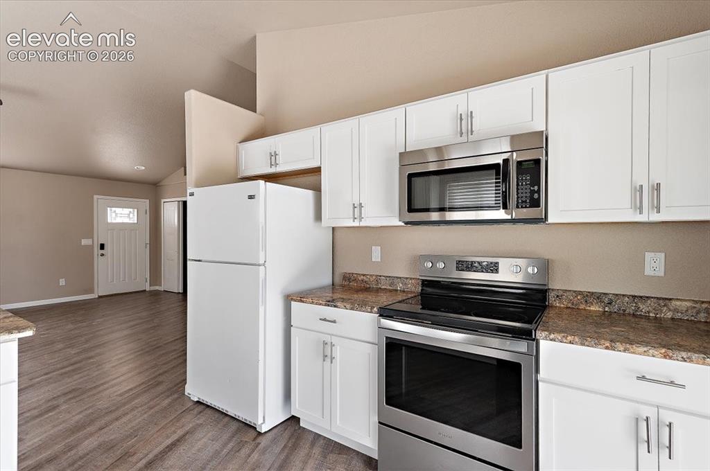 Image 6 of 21: Kitchen featuring white cabinetry, stainless steel microwave, and electric