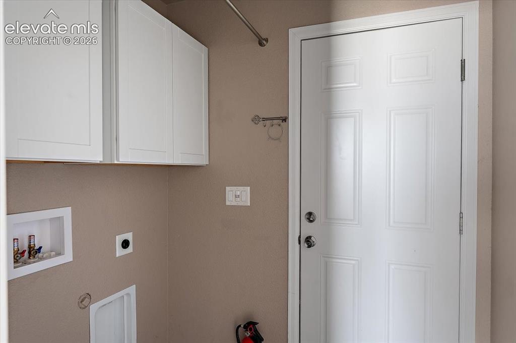 Image 9 of 21: Utility area featuring built-in white shaker-style cabinetry, a paneled whi