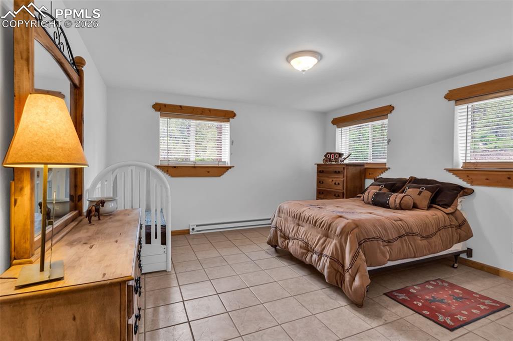 Image 34 of 49: Large lower level bedroom with tile floors and garden level windows