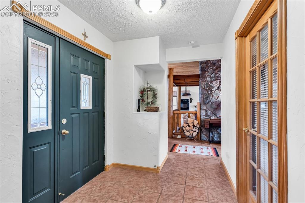 Image 8 of 49: Tile floors and coat closet upon entry, with glass door to the office/livin