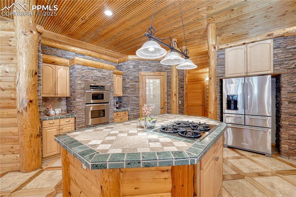 Image 13 of 50: Island with 4 burner gas cooktop, a large refrigerator, walk-in pantry and