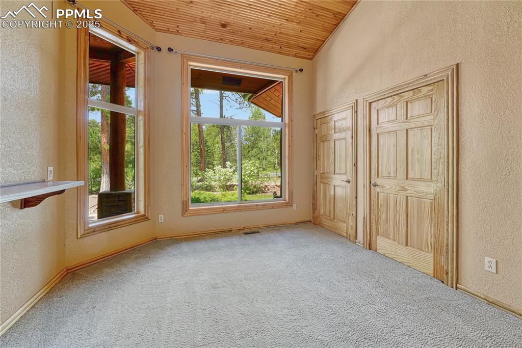 Image 21 of 50: First bedroom off the entry with 2 closets, carpeted floors, tall wood ceil