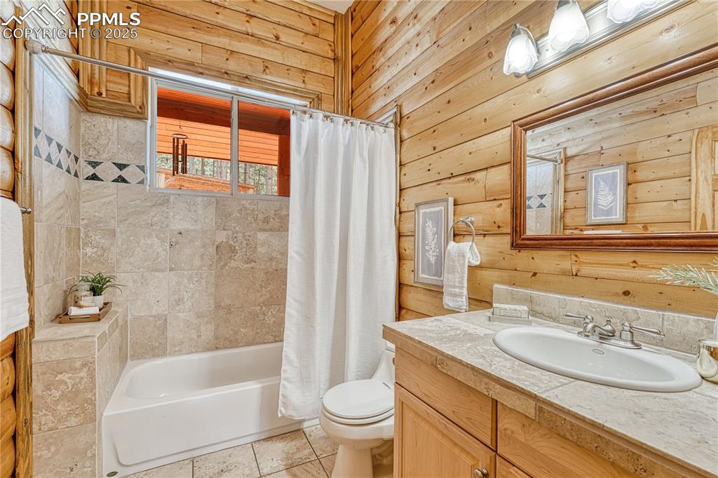 Image 22 of 50: Full bathroom with travertine tile counters and shower/tub surround across