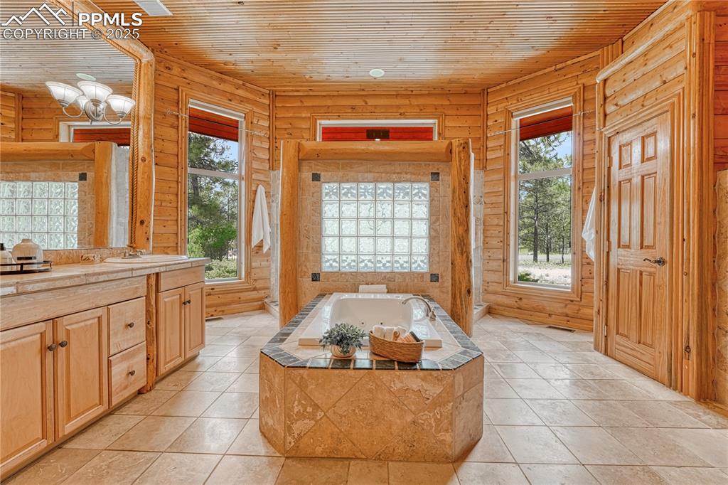 Image 25 of 50: Adjoining Primary Spa Bathroom features a jet tub centerpiece and dual-side