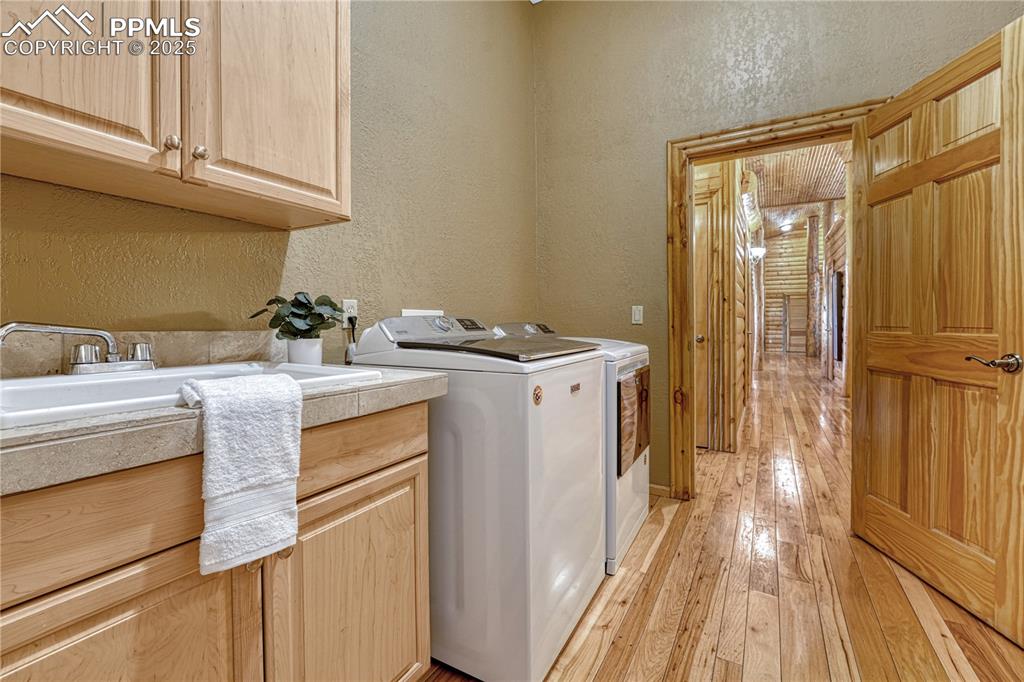 Image 36 of 50: Large laundry room with utility sink and electric hookups off the garage