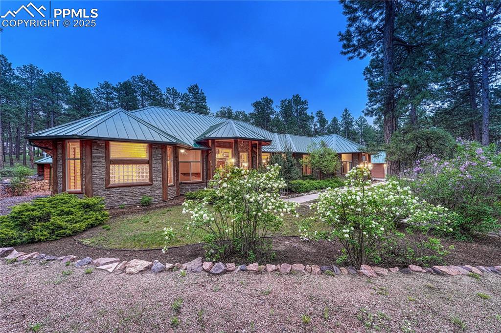 Image 4 of 50: A custom home with stacked stone and log exterior and metal roof