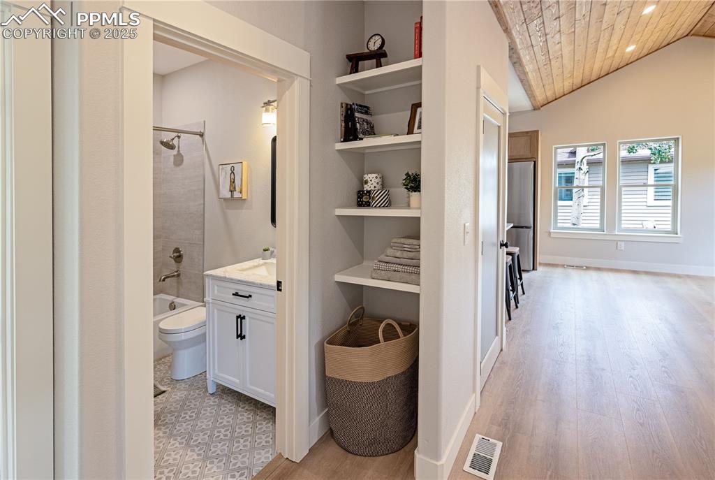 Image 11 of 21: Corridor featuring linen closet, lofted ceiling, light LV flooring, and woo