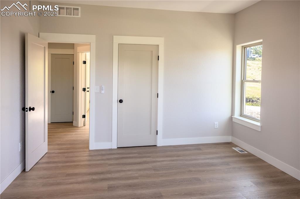 Image 16 of 21: Primary bedroom entry door and walk-in closet door. Ceiling fan.