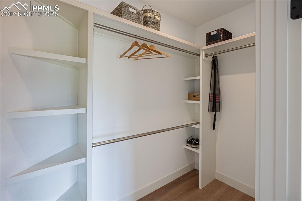 Image 17 of 21: Primary bedroom walk in closet with built in shelving and LV plank floors