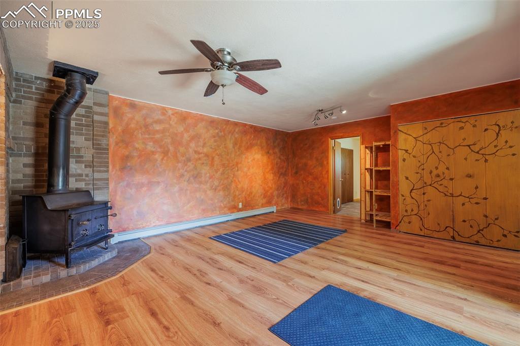 Image 11 of 32: Walk out living room with a wood stove, a ceiling fan 