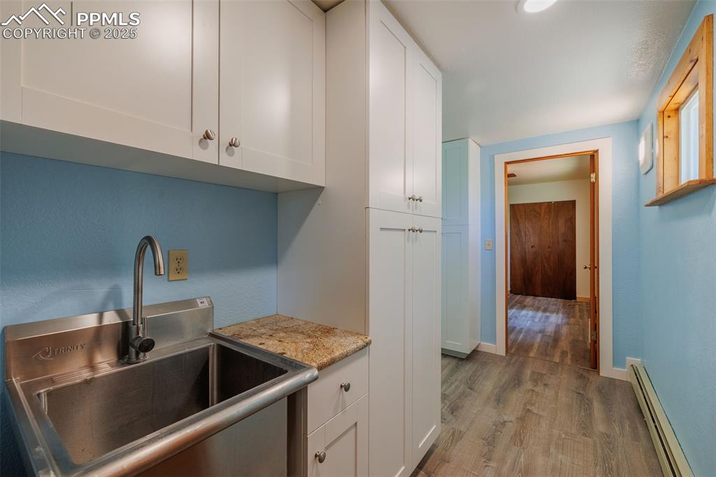 Image 21 of 32: Kitchen with a baseboard radiator, light wood-type flooring, white cabinetr