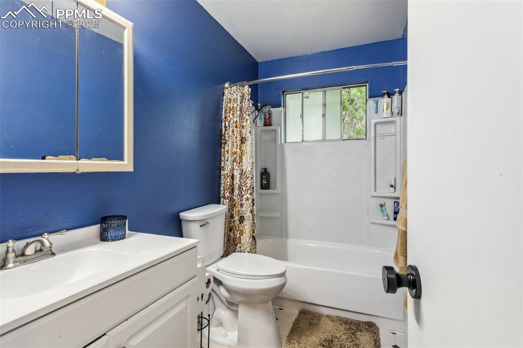 Image 10 of 20: Bathroom featuring toilet, vanity, shower / tub combo with curtain, a textu