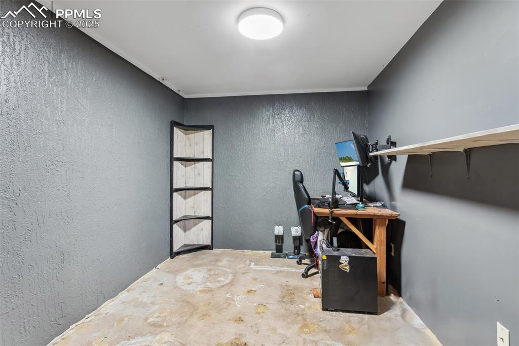 Image 11 of 20: Office featuring unfinished concrete floors and a textured wall
