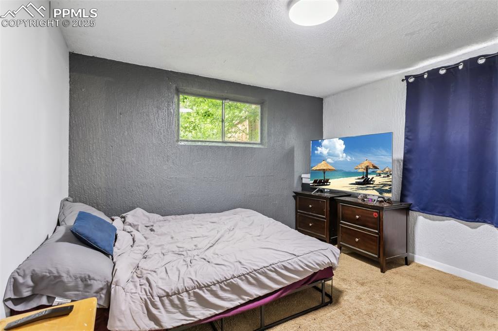 Image 13 of 20: Bedroom with carpet flooring, a textured ceiling, a textured wall, and base
