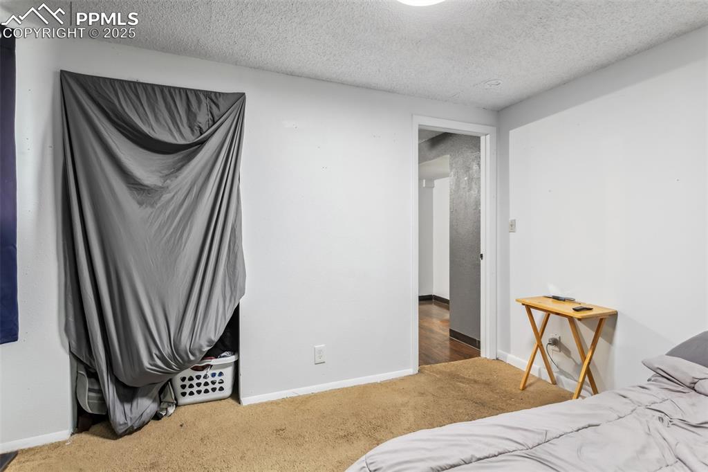 Image 14 of 20: Carpeted bedroom with a textured ceiling and baseboards