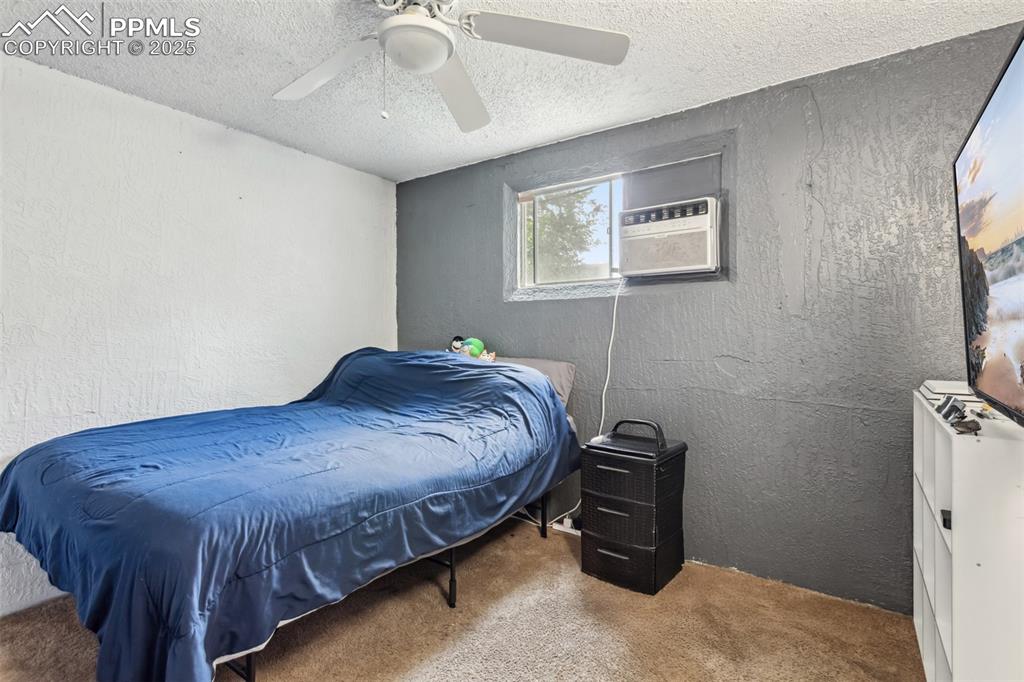 Image 15 of 20: Bedroom featuring carpet, a textured ceiling, a textured wall, an AC wall u