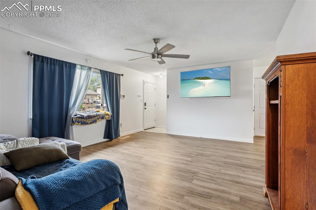 Image 3 of 20: Living area featuring ceiling fan, light wood-type flooring, baseboards, an